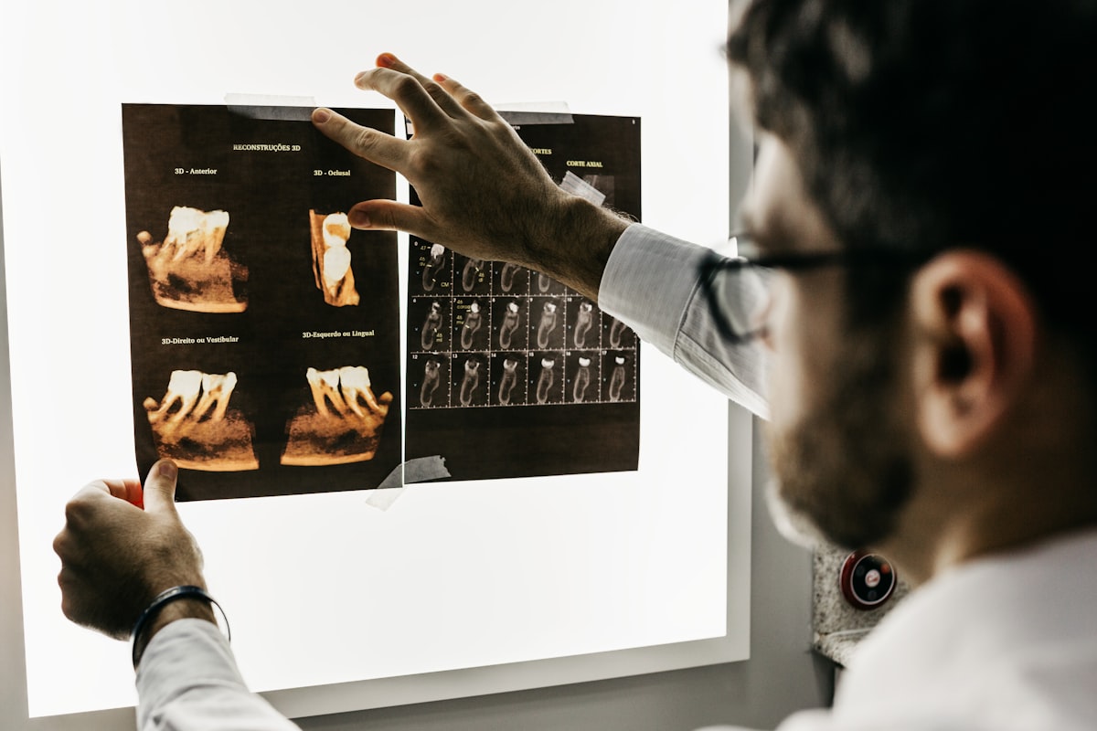 A clinician examining dental X-ray films on a light board